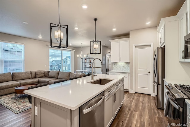 kitchen featuring a sink, stainless steel appliances, dark wood-style floors, open floor plan, and recessed lighting