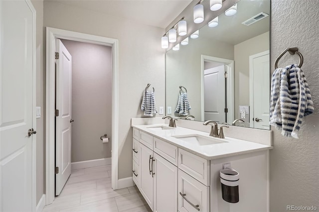full bath featuring double vanity and baseboards