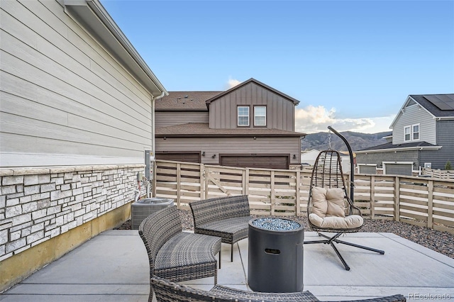 view of patio featuring cooling unit, fence, and a garage