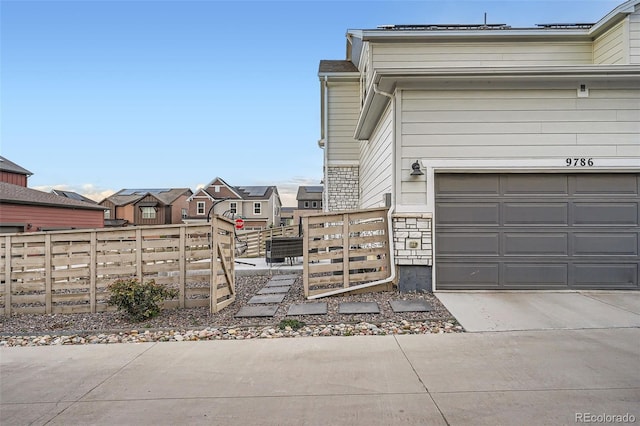 view of side of property with fence, driveway, a garage, and stone siding