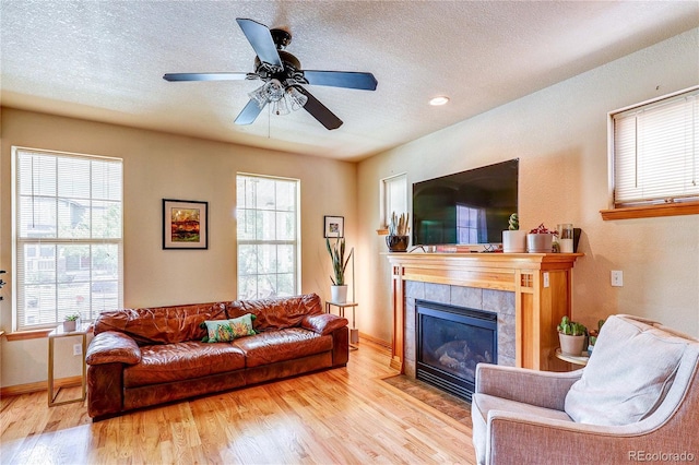 3354 Wabash St, Denver, CO 80238 - living room featuring wood finished floors, a tile fireplace, a textured ceiling, and ceiling fan