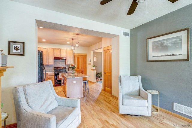 3354 Wabash St, Denver, CO 80238 - kitchen featuring black / electric stove, light wood-type flooring, ceiling fan, a breakfast bar area, and refrigerator