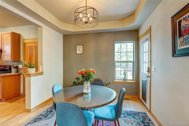 3354 Wabash St, Denver, CO 80238 - dining space featuring light wood-style floors, a chandelier, a textured wall, and a tray ceiling