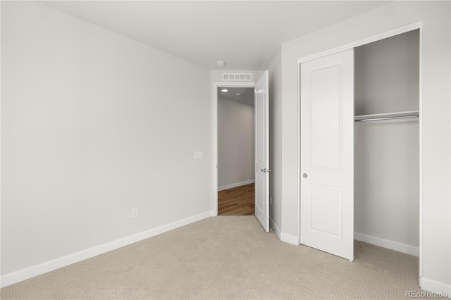 unfurnished bedroom with a closet and light carpet