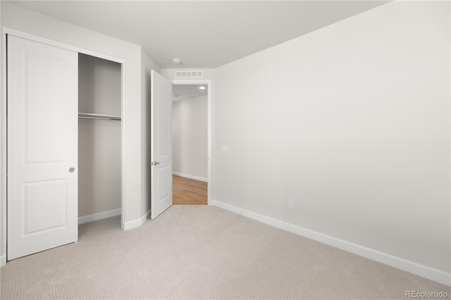 unfurnished bedroom featuring a closet and light carpet