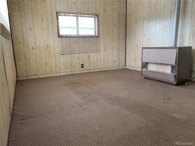 carpeted spare room with wooden walls and heating unit