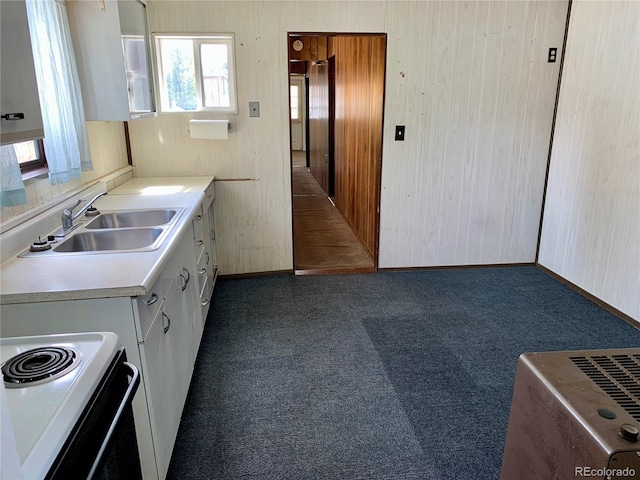 kitchen with dark carpet, light countertops, white electric stove, white cabinetry, and a sink