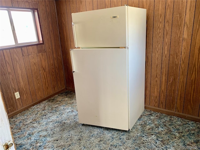 kitchen featuring carpet, wood walls, and freestanding refrigerator