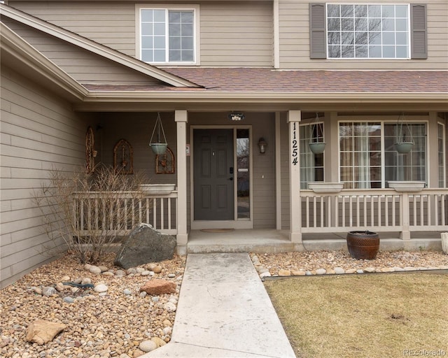 doorway to property featuring a shingled roof and a porch