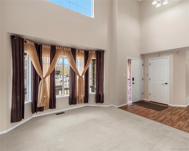carpeted foyer with baseboards, a healthy amount of sunlight, and visible vents