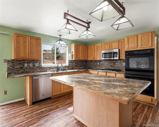 kitchen with stainless steel appliances, tasteful backsplash, dark wood-type flooring, a sink, and a center island