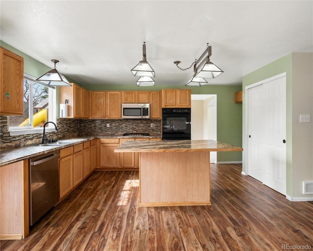 kitchen with stainless steel appliances, a center island, a sink, dark wood-style floors, and backsplash