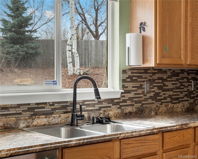 interior details featuring a sink, brown cabinetry, and tasteful backsplash