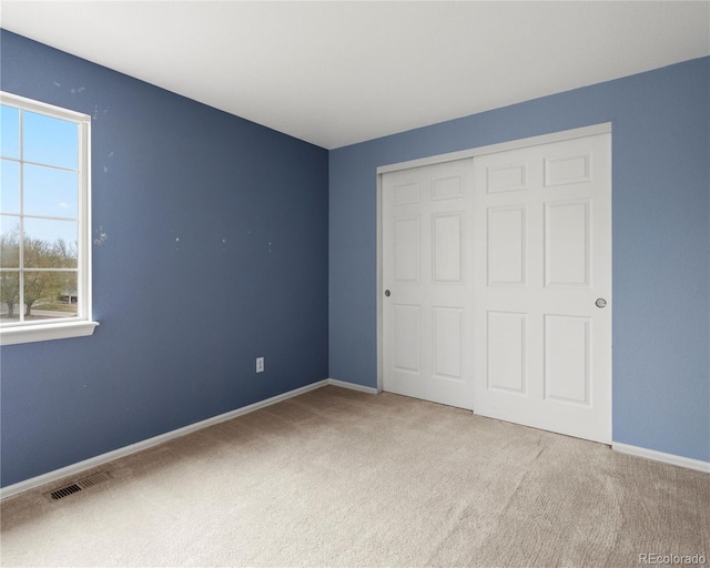 unfurnished bedroom with baseboards, visible vents, a closet, and carpet