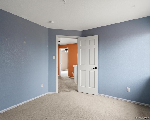 carpeted spare room with baseboards and ceiling fan