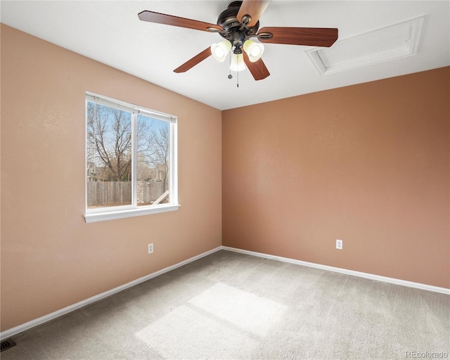 carpeted spare room with attic access, baseboards, visible vents, and ceiling fan