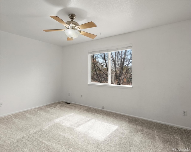 carpeted empty room with baseboards, visible vents, and ceiling fan