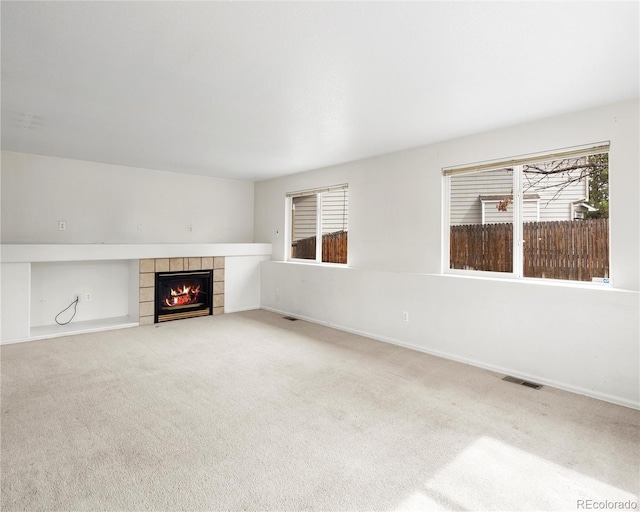 unfurnished living room featuring baseboards, a fireplace, visible vents, and light colored carpet