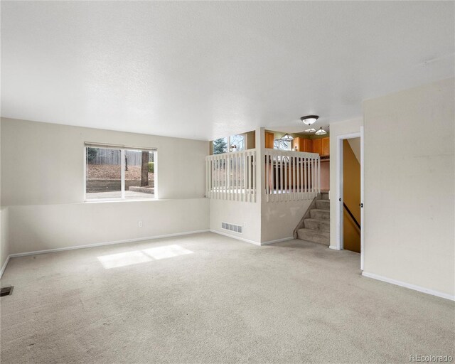 unfurnished living room with baseboards, visible vents, and light carpet