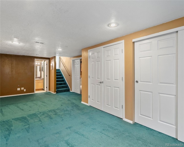 finished below grade area with stairs, baseboards, carpet flooring, and a textured ceiling
