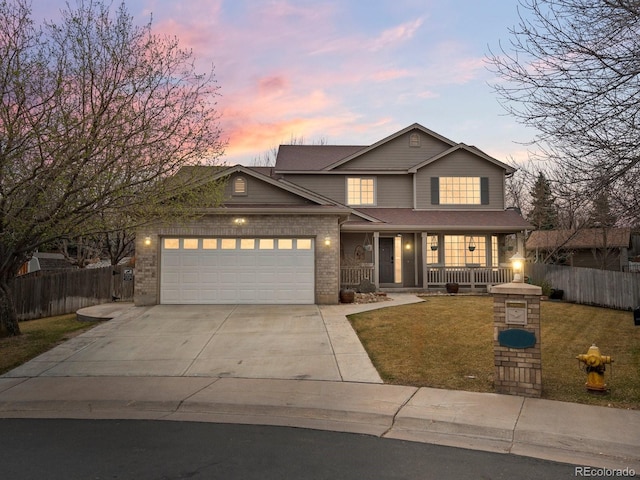traditional-style home featuring driveway, covered porch, fence, and a front yard
