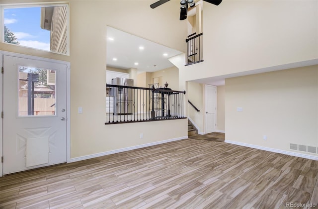 foyer with a high ceiling, light hardwood / wood-style floors, and ceiling fan