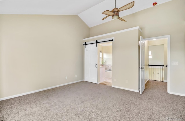 unfurnished bedroom with a barn door, ensuite bathroom, vaulted ceiling, and carpet floors