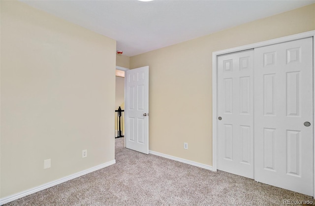 unfurnished bedroom with light colored carpet and a closet