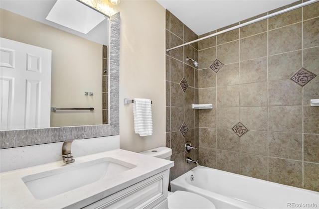 full bathroom featuring a skylight, vanity, tiled shower / bath combo, and toilet