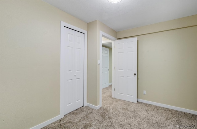 unfurnished bedroom featuring light colored carpet, a textured ceiling, and a closet