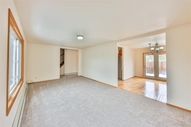 spare room featuring light hardwood / wood-style flooring, baseboard heating, and an inviting chandelier