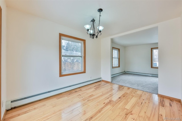 spare room with a baseboard heating unit, light hardwood / wood-style floors, and a wealth of natural light