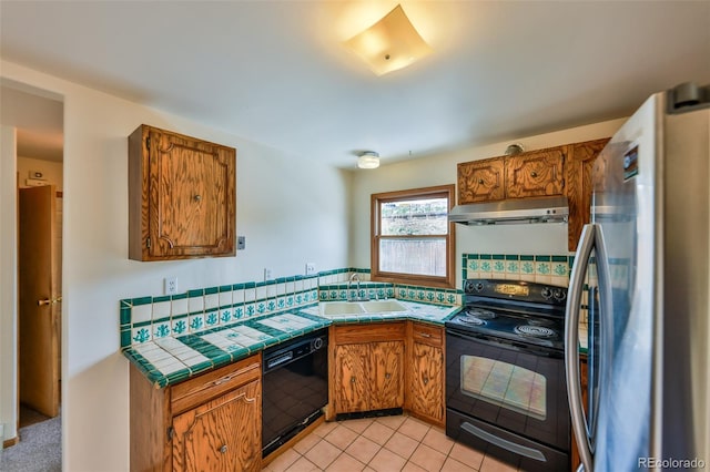 kitchen with sink, light carpet, black appliances, and tile countertops