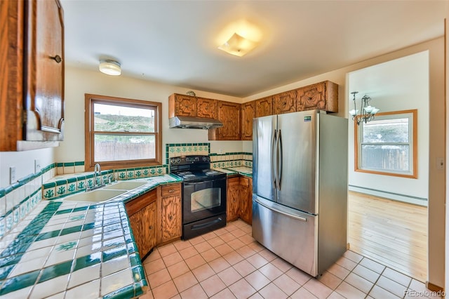 kitchen with range hood, a baseboard radiator, stainless steel fridge, black electric range oven, and sink