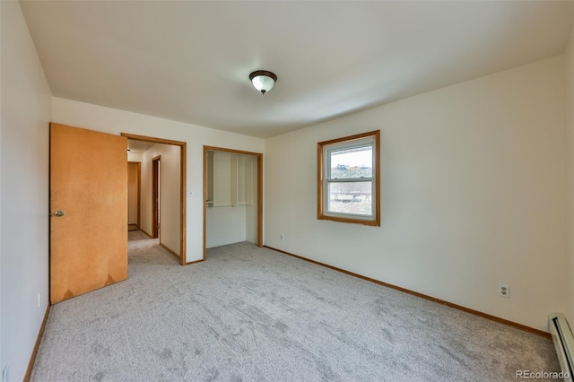 unfurnished bedroom with a baseboard heating unit, carpet, and a closet