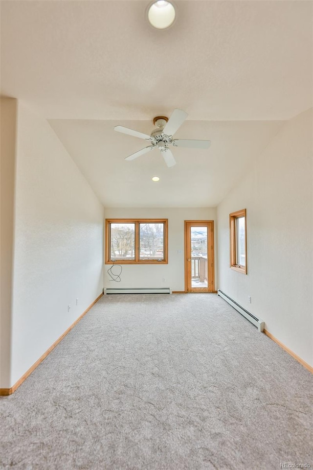 carpeted empty room featuring vaulted ceiling, ceiling fan, and a baseboard heating unit