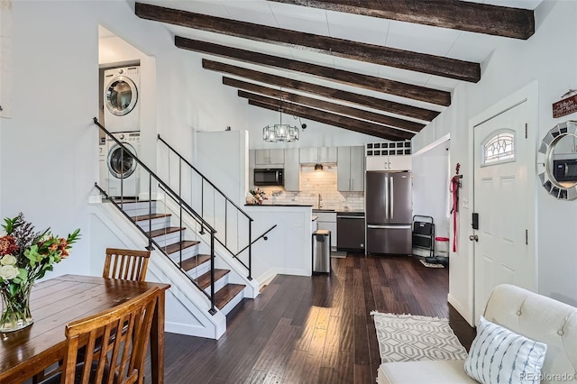 interior space with dark hardwood / wood-style flooring, high vaulted ceiling, a notable chandelier, beamed ceiling, and stacked washer / drying machine