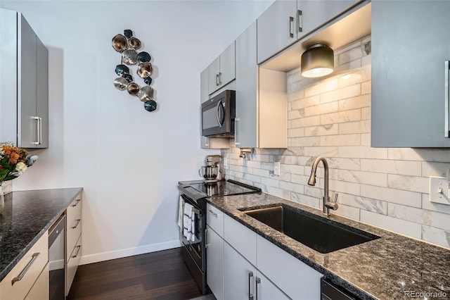 kitchen featuring sink, tasteful backsplash, dark hardwood / wood-style floors, dark stone counters, and black appliances