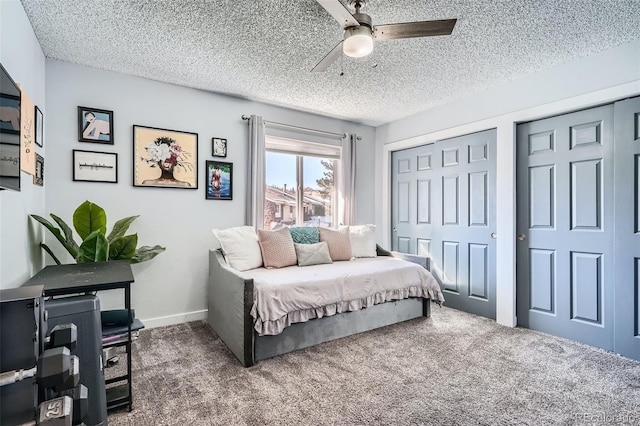 carpeted bedroom featuring two closets, ceiling fan, and a textured ceiling