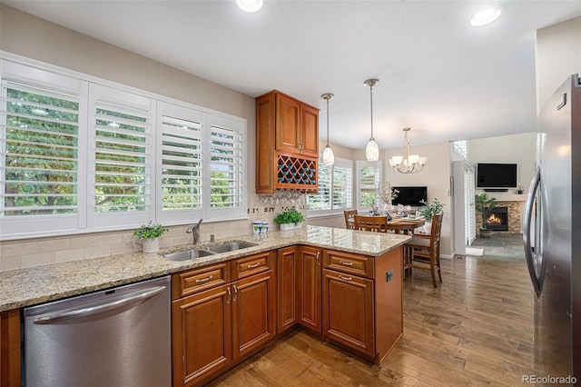 6836 Poppy Ct, Arvada, CO 80007 - kitchen featuring appliances with stainless steel finishes, brown cabinetry, wood finished floors, backsplash, and recessed lighting