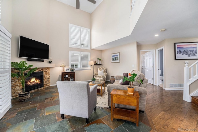 6836 Poppy Ct, Arvada, CO 80007 - living area featuring a glass covered fireplace, a towering ceiling, ceiling fan, stairs, and healthy amount of natural light