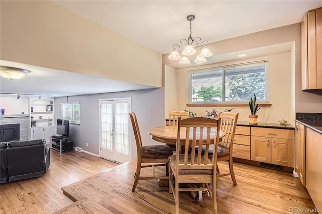 13123 Spica Dr, Lone Tree, CO 80124 - dining room featuring light wood-type flooring, a chandelier, and a glass covered fireplace
