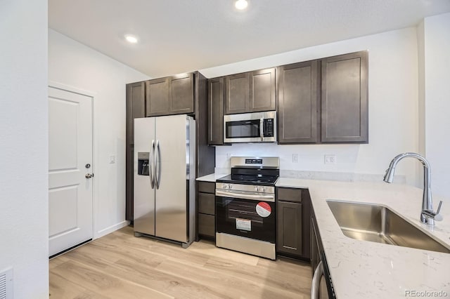 1974 S Haleyville Way, Aurora, CO 80018 - kitchen featuring appliances with stainless steel finishes, a sink, dark brown cabinets, light wood-type flooring, and light stone countertops