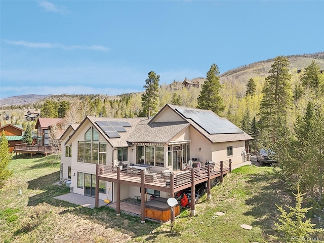 50 Spinning Leaf Trl, Silverthorne, CO 80498 - rear view of house featuring solar panels, a deck with mountain view, stucco siding, a yard, and a hot tub