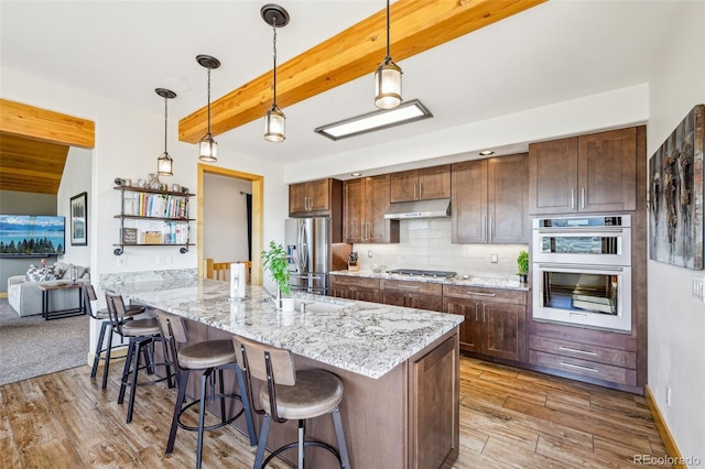50 Spinning Leaf Trl, Silverthorne, CO 80498 - kitchen featuring stainless steel appliances, under cabinet range hood, beam ceiling, a breakfast bar area, and light wood-type flooring