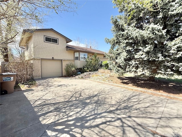tri-level home with an attached garage, concrete driveway, and brick siding