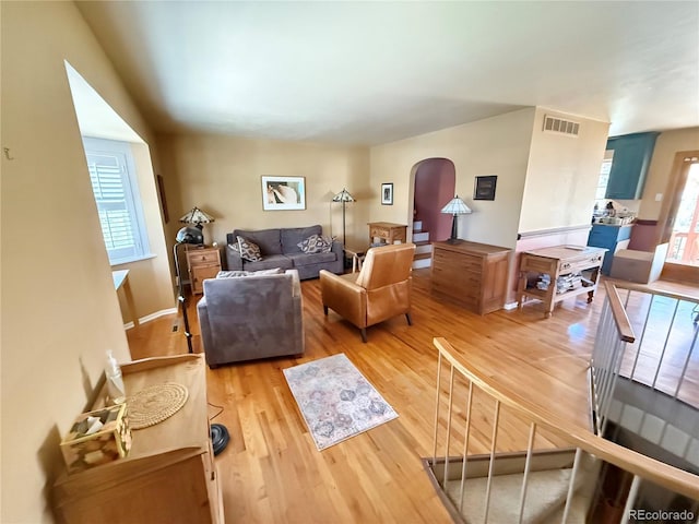 living room featuring arched walkways, visible vents, and wood finished floors