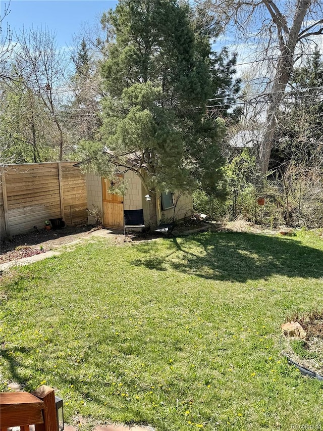 view of yard with a storage shed, fence, and an outbuilding
