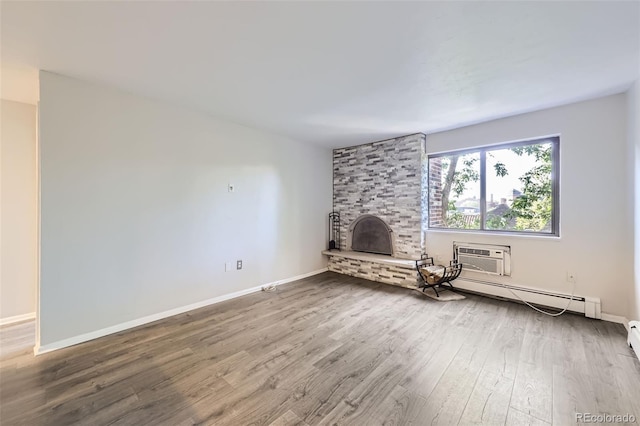1008 N Corona St Unit 403, Denver, CO 80218 - unfurnished living room featuring a baseboard heating unit, an AC wall unit, wood finished floors, a fireplace, and baseboards
