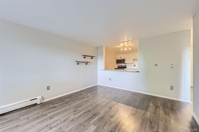 1008 N Corona St Unit 403, Denver, CO 80218 - unfurnished living room featuring wood finished floors, a baseboard radiator, and baseboards